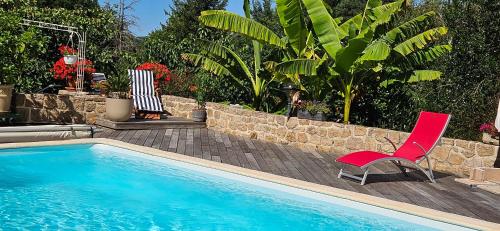 a red chair sitting next to a swimming pool at Chambre d'hôtes un petit coin de paradis en Corrèze in Laguenne