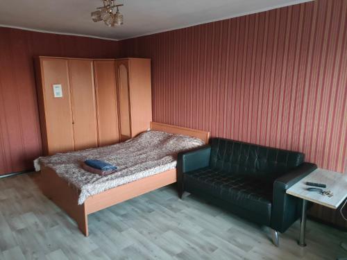 a small bedroom with a bed and a couch at Galeto 22 Apartments in Semey