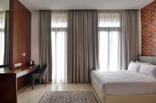 マスジッド・タナにあるElshape Holiday VILLAのベッド、デスク、窓が備わるホテルルームです。