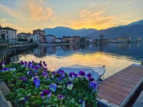 a boat is docked on a lake with purple flowers at Il Cavallino, sul lago Ceresio in Brusimpiano
