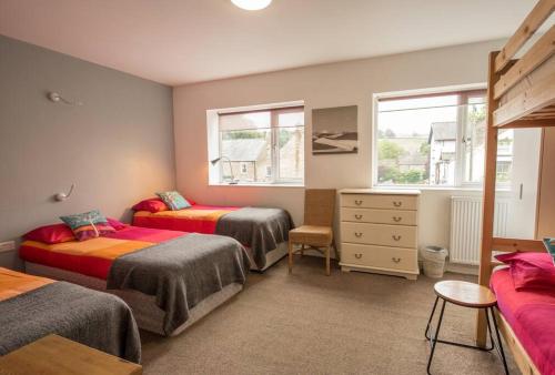 a bedroom with two beds and a dresser and two windows at The Allendale Bunkhouse in Hexham