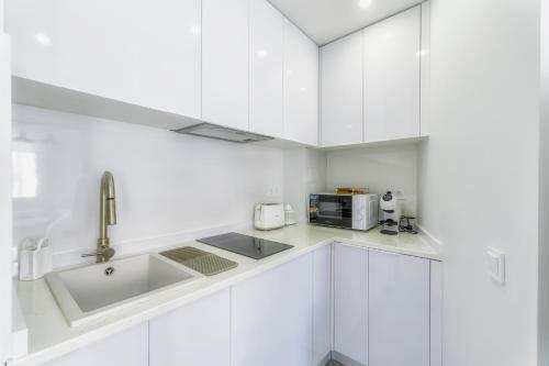 a white kitchen with a sink and a microwave at Playa Del Cura Apartment in Torrevieja