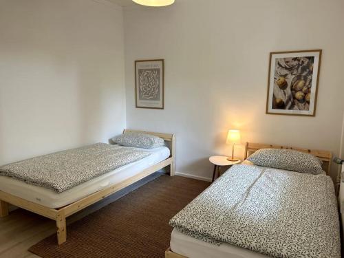 Zimmer mit 2 Betten und einem Tisch mit einer Lampe in der Unterkunft Country style apartment with balcony near fair in Hannover