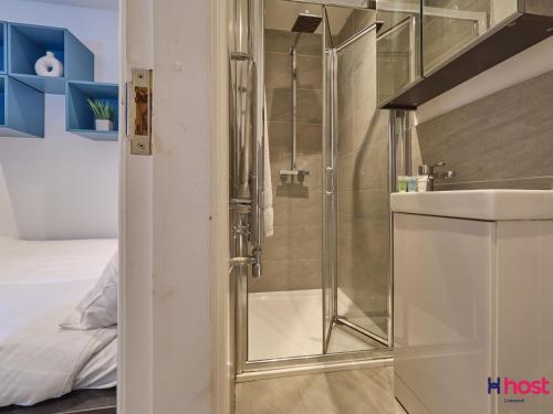 a shower with a glass door next to a bed at Host Liverpool - Cozy CoLiving, Connect & Enjoy in Liverpool