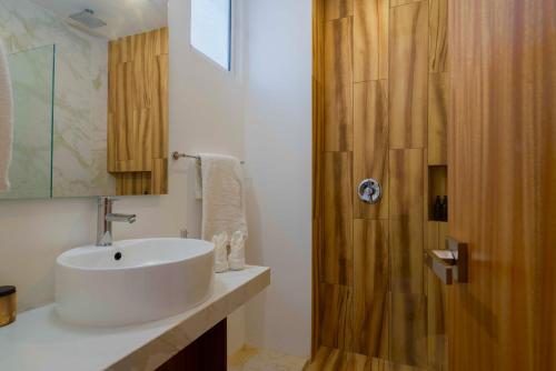 ein Badezimmer mit einem weißen Waschbecken und einer Holztür in der Unterkunft Beautiful Swim-Up Apartment with Private Terrace & Hammoc, Pool & Gym in Tulum