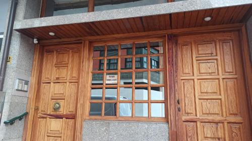 une porte en bois avec des fenêtres en verre dans un bâtiment dans l'établissement Apartamento Casa Belén Arriondas, à Arriondas
