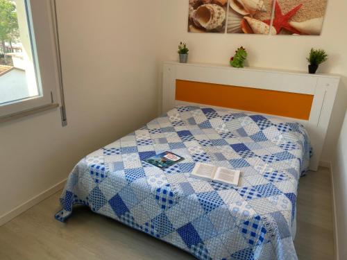 a bedroom with a bed with a blue and white quilt at ANTONELLA PLUS in Bibione