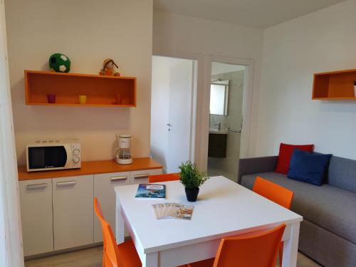 a small living room with a white table and orange chairs at ANTONELLA PLUS in Bibione