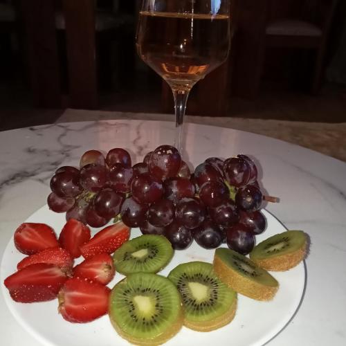 a plate of fruit with a glass of wine at Jaymorgan' cabins in Nyeri