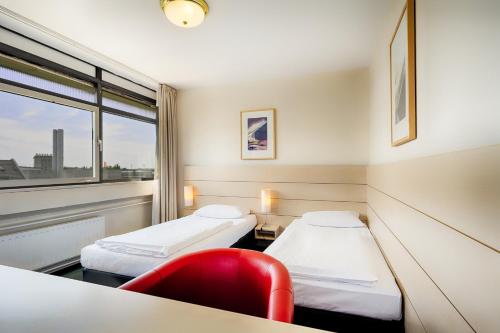 a hospital room with two beds and a red chair at Enjoy Hotel am Studio in Berlin