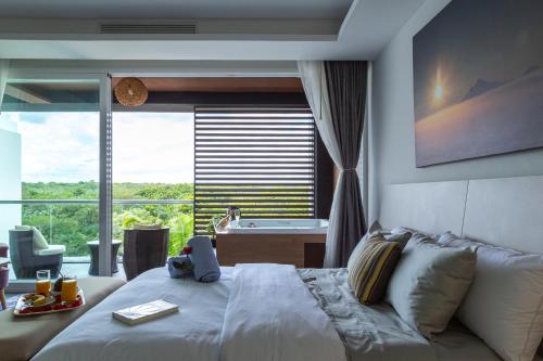 um quarto com uma cama, uma banheira e uma janela em Fabulous & Exclusive Apartments With Sea View Pool BBQ Garden em Akumal