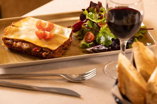a plate of food with a salad and a glass of wine at Hôtel Esté in Paris
