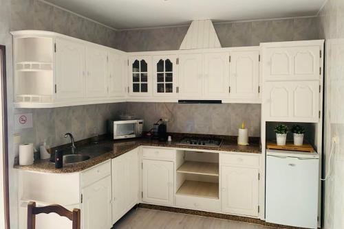 Una cocina blanca con gabinetes blancos y un fregadero. en Casa da Vila Guest House, en Póvoa de Varzim