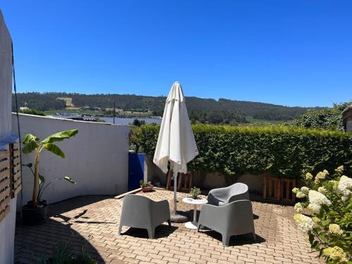 eine Terrasse mit einem Sonnenschirm, 2 Stühlen und einem Tisch in der Unterkunft Casa da Vila Guest House in Póvoa de Varzim