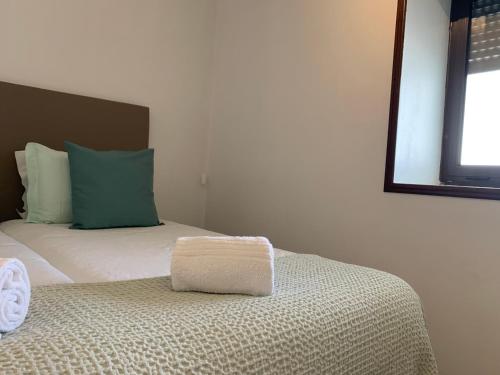 a bedroom with a bed with a green pillow on it at Casa da Vila Guest House in Póvoa de Varzim