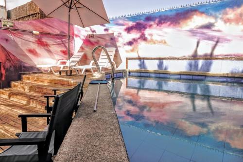 Aotea Hostel Iquique في إكيكي: مسبح مع كراسي ومظلة بجانب طاولة