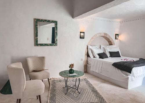um quarto com uma cama, uma mesa e uma cadeira em Dar Naël em Houmt Souk