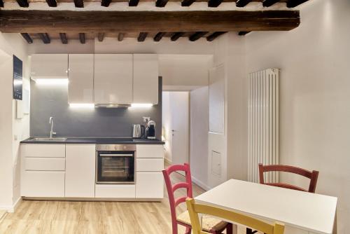 a kitchen with white cabinets and a table and chairs at Casa Monelli in Siena