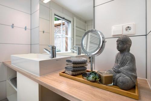 - une salle de bains avec une statue assise sur un comptoir avec un miroir dans l'établissement Gutenburghüsli mit Garten am Fluss, à Waldshut-Tiengen
