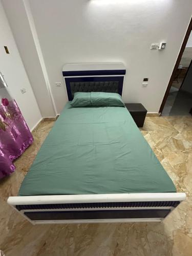 a bed with a green mattress in a room at مبيت Mabeet - شقق ستديو in 6th Of October