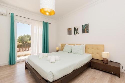a white bedroom with a large bed and a window at Solar Santo Antonio in Palmela