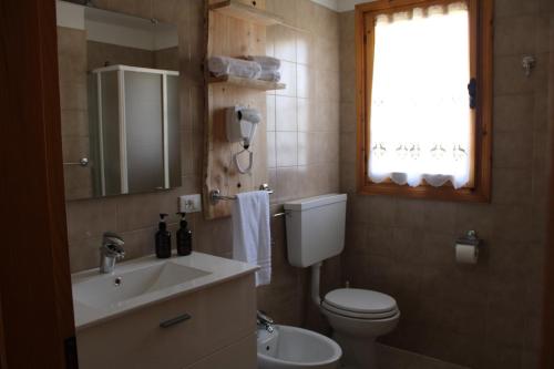 baño con lavabo y aseo y ventana en I profumi del bosco, en Enego