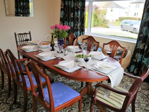 a wooden table with chairs and a table with wine glasses at Braidwood in Castle Douglas