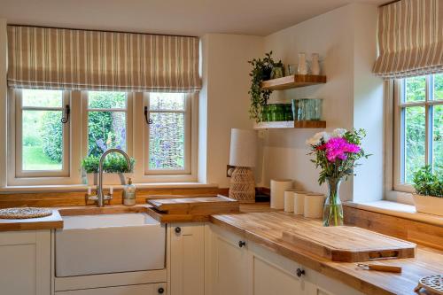 a kitchen with a sink and a vase of flowers at Finest Retreats - Manor Cottage in Winterborne Stickland