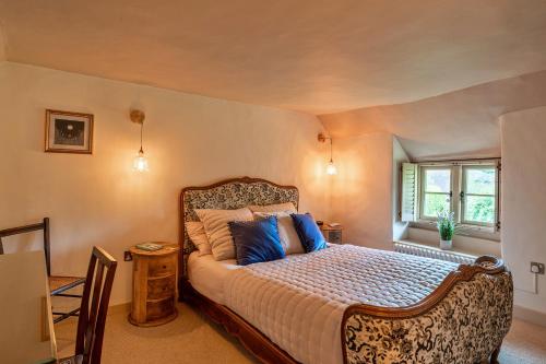 a bedroom with a large bed with blue pillows at Finest Retreats - Manor Cottage in Winterborne Stickland
