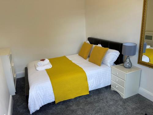a bedroom with a bed with a yellow blanket and a mirror at Robinhuts - 3 Bed Accommodation -Perfect for Contractors, Families & Students in Hull