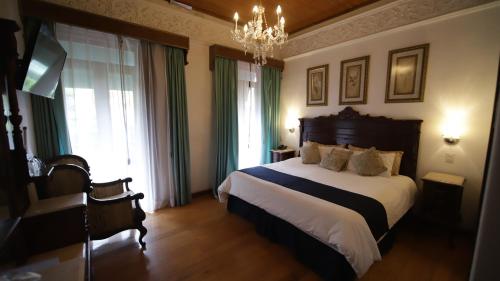 a bedroom with a large bed and a chandelier at Hotel Luna in Guanajuato