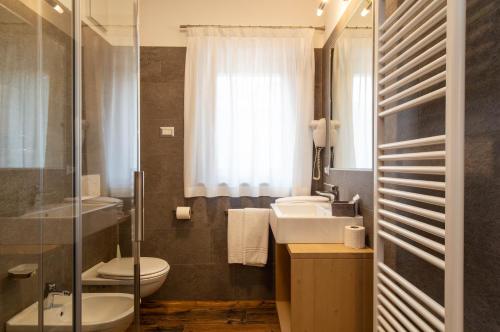 a bathroom with a sink and a toilet and a mirror at San Martino Mountain Residence in San Martino di Castrozza