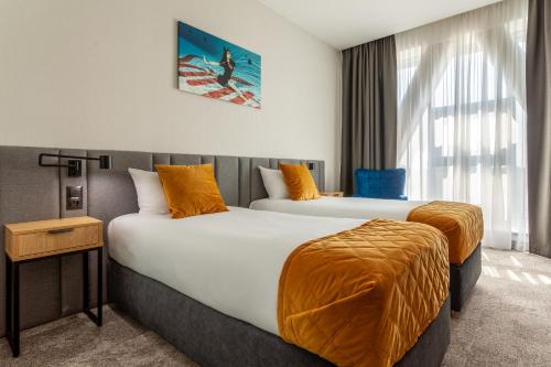 Habitación de hotel con 2 camas con sábanas de color naranja en Hotel Sante en Varsovia