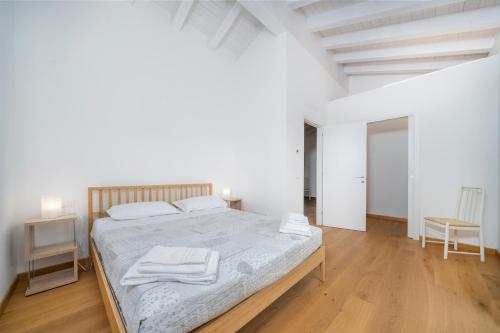 um quarto branco com uma cama e piso em madeira em The House of Antonietta em Udine