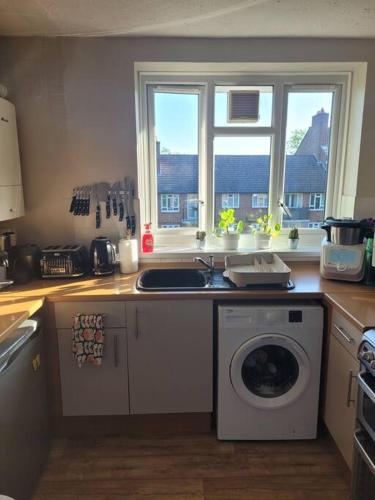 a kitchen with a sink and a washing machine at Comfortable two bedroom flat in Putney. in London