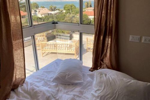 a bed in a bedroom with a view of a balcony at Earth & Heavens in Kinneret