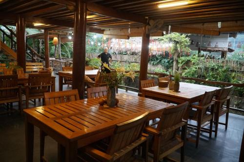 a restaurant with wooden tables and chairs and a man in the background at Jack Ecolodge in Lung Co (1)