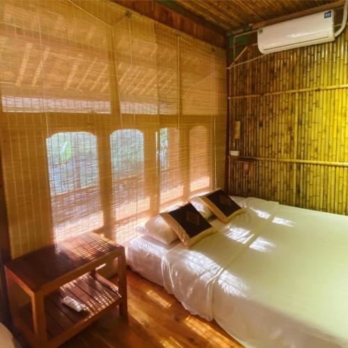 a bedroom with a bed in a room with windows at Jack Ecolodge in Lung Co (1)
