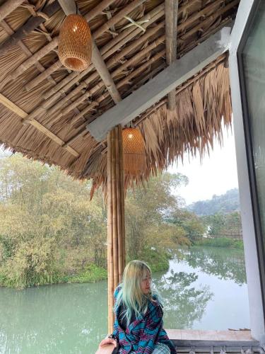 a woman sitting on a porch with a view of a river at Jack Ecolodge in Lung Co (1)