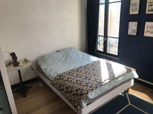 a bed in a room with a table and a window at Porte de Paris - Saint-Denis quartier historique in Saint-Denis