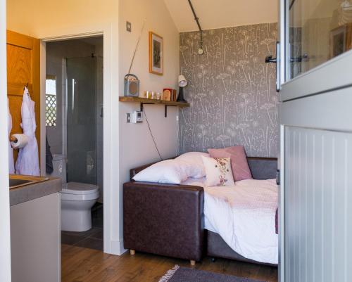 a small bedroom with a bed and a bathroom at Daisy Bank Camp in Hebden Bridge
