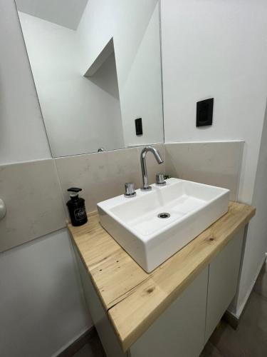 y baño con lavabo blanco y espejo. en Departamento Plaza en San Martín