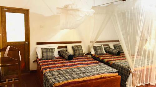 1 dormitorio con 2 camas, cortinas y ventana en Sisira Natural Lodge - Sigiriya, en Sigiriya