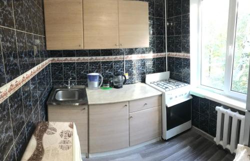 een kleine keuken met een wastafel en een fornuis bij квартира на набережной in Alma-Ata