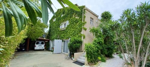 uma casa coberta de hera verde com uma porta branca em Chambre d hôte avec piscine em Agde