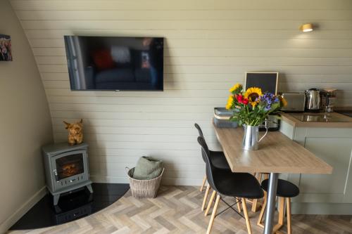 a kitchen with a table with flowers and a television at Glengolly Getaways in Thurso