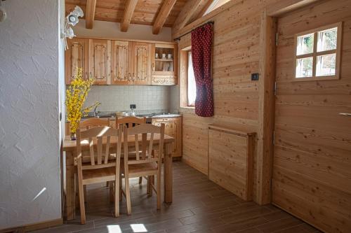 una cucina con armadi in legno, tavolo e sedie di Chalet Camping Faè 2 a Madonna di Campiglio