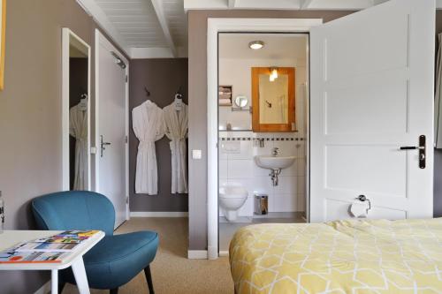 a bedroom with a bed and a bathroom with a sink at B&B - Sauna D'Olle Pastorie in Vierhuizen
