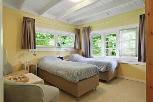 a bedroom with two beds and a couch and windows at B&B - Sauna D'Olle Pastorie in Vierhuizen