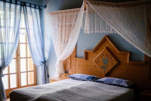 - une chambre avec un lit doté d'une tête de lit en bois et d'une fenêtre dans l'établissement Agritur Maso alle Rose B&B e Restaurant, à Fiavè